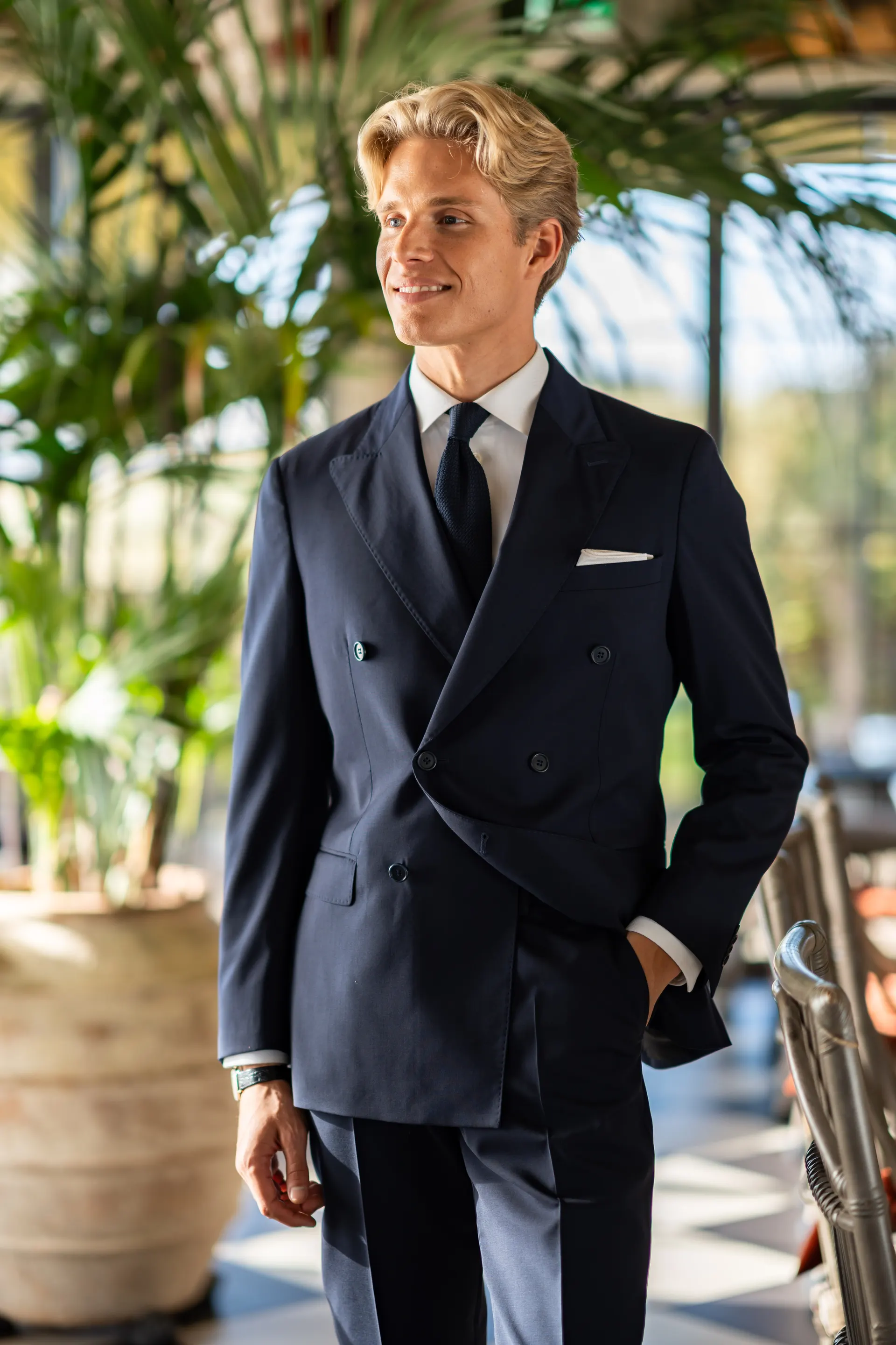 Smilende mann i marineblå dobbeltspent dress med slips og hvitt lommetørkle.